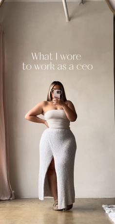 Woman in a strapless top and ribbed skirt with a high slit taking a mirror selfie
