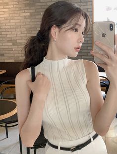 Woman taking a selfie in a white ribbed top and black belt