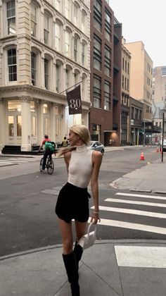 Blonde woman in a white top and black shorts on a city street
