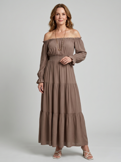 Woman in a brown off-shoulder maxi dress with gold jewelry and white heels