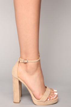 Woman's foot in beige high heels with an ankle strap and white toenails