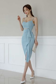Woman in a light blue dress and white high heels holding a clutch bag