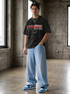 Man in an oversized t-shirt and baggy jeans standing in an indoor concrete space