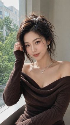 Woman in an off-shoulder top with a messy bun, looking at the camera