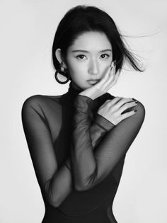 Woman in a sheer black top and large earrings posing in a studio