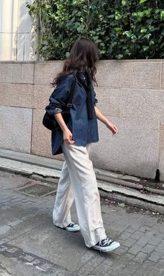 Person in a denim shirt and wide leg pants walking outdoors