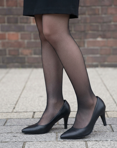 Lower body of a person wearing a black skirt, pantyhose, and heels outdoors