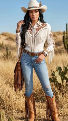 Woman in a cowboy hat, fringe shirt, and jeans in a desert landscape