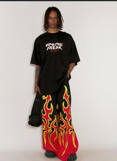 Person with dreadlocks wearing a black t-shirt and flame print pants