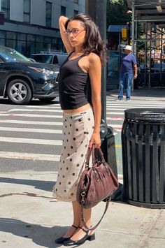 Woman in a black tank top and polka dot skirt on a sunny street