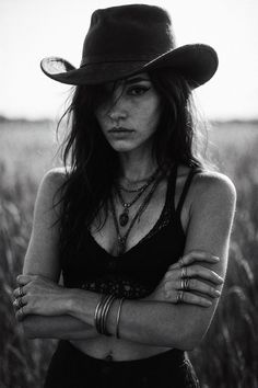 Woman in a cowboy hat and crochet top with arms crossed, outdoor shot
