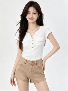 Woman with long dark hair wearing a white shirt and brown shorts in a studio