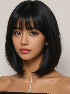 Woman with short black hair and bangs wearing a necklace