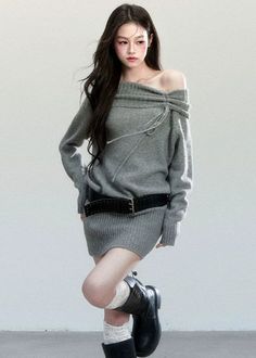 Woman in a gray off-shoulder sweater dress with a black belt and boots