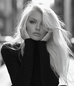 Woman with long blonde hair in a black sweater, shot in monochrome with backlight