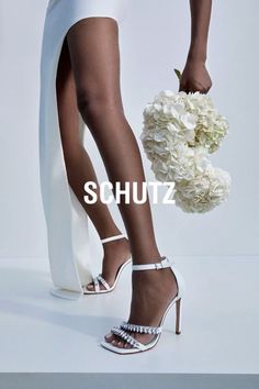 Woman in a white dress and high heels holding white flowers