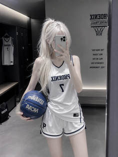 Woman in a white basketball uniform holding a blue basketball in a locker room