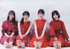 Four women in red dresses sitting on the floor with bare feet
