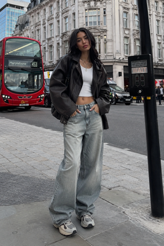 Woman in a leather jacket and baggy jeans on a city street