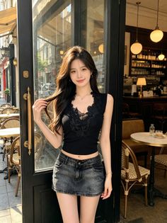Woman in a black top and denim skirt standing outside a cafe