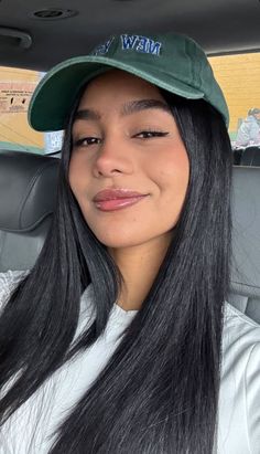 Woman with long black hair and a green hat in a car interior