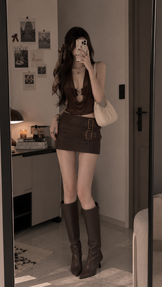 Woman in a brown mini skirt and draped top taking a mirror selfie