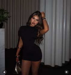 Woman in a black dress with long hair posing indoors