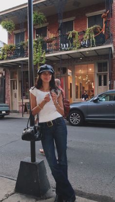 Woman in a white top, jeans, and hat standing on a street