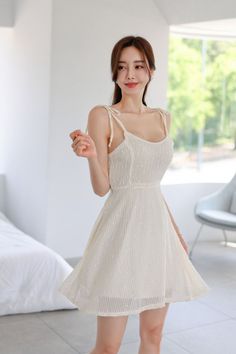 Woman in a white dress with tied straps posing indoors