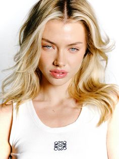Blonde woman with blue eyes wearing a white tank top