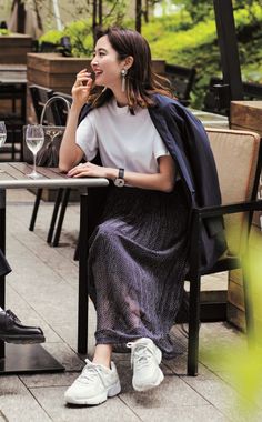 Woman in a polka dot skirt and white t-shirt sitting at an outdoor cafe
