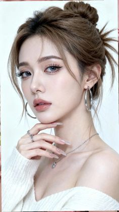 Woman with brown hair in a messy bun, wearing a white sweater and jewelry