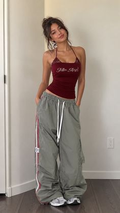 Woman in a red halter top and baggy pants posing indoors