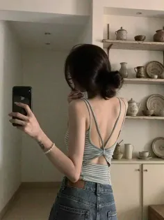 Woman with bun hair taking a mirror selfie in a striped top and jeans