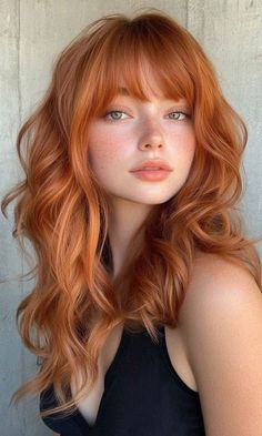 Woman with long red hair and freckles wearing a black top