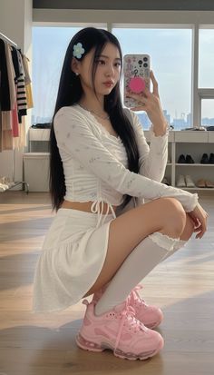 Woman in a white crop top and mini skirt taking a mirror selfie
