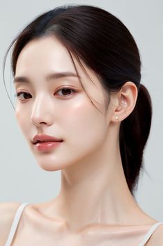 Woman with dark hair in a ponytail wearing small earrings, looking to the side