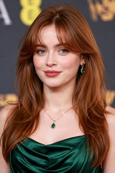 Woman with red hair wearing a green dress and emerald jewelry