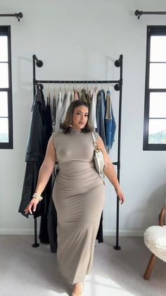 Woman in a beige maxi dress posing in an indoor setting with a clothing rack