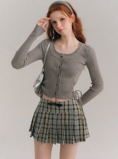 Woman with red hair wearing a plaid skirt and crop top in a studio