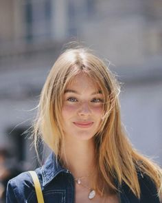 Young woman with blonde hair and freckles wearing a denim jacket and necklace