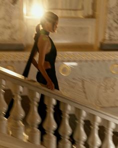 Woman in a black dress walking down an elegant staircase with backlight