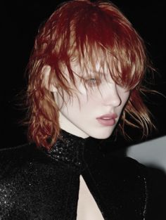 Woman with shaggy red hair and a sparkling black high-collar top