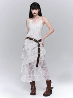 Woman in a white ruffled lace dress and brown boots posing in a studio