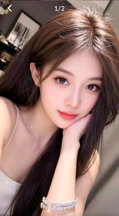 Woman with long brown hair wearing a white top and sparkling bracelets