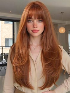 Woman with long red hair and bangs wearing a collared shirt indoors