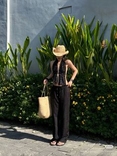Woman in a straw hat and black halter top with a straw bag outdoors