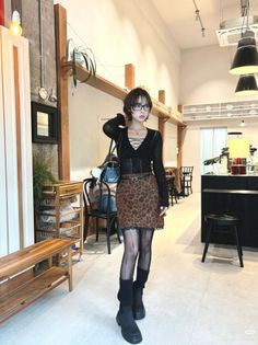 Woman in a leopard print skirt and black top posing in a cafe