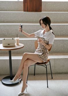 Woman in a plaid dress and high heels taking a selfie indoors