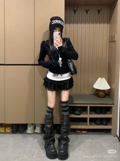Person in a black hoodie, ruffle skirt, and platform boots taking a mirror selfie